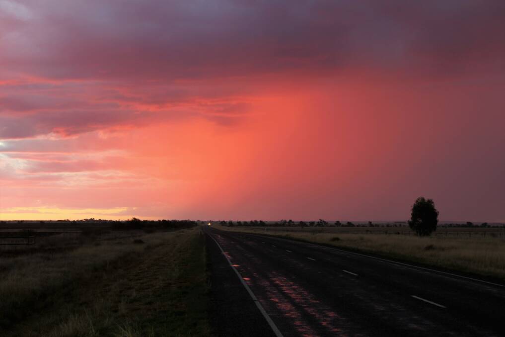 Red sky at night: The patchy storms extended north as far as Tambo, where this clearing shower cast a rosy glow over the landscape at sunset. Picture: Sally Cripps.