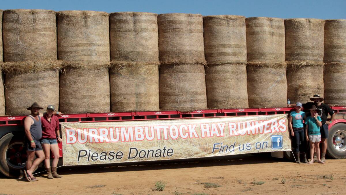 Truck drivers from Moss Vale display the fundraising sign they made for their local show in Sydney, and the hay they unloaded directly at an Ilfracombe property.