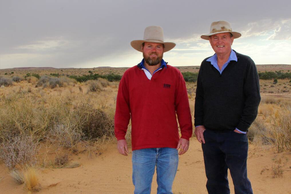 Team work: David Brook, right, and son Anthony, the company's operations manager,  watch as winter showers tease the sand dunes around Birdsville. Picture: Sally Cripps.