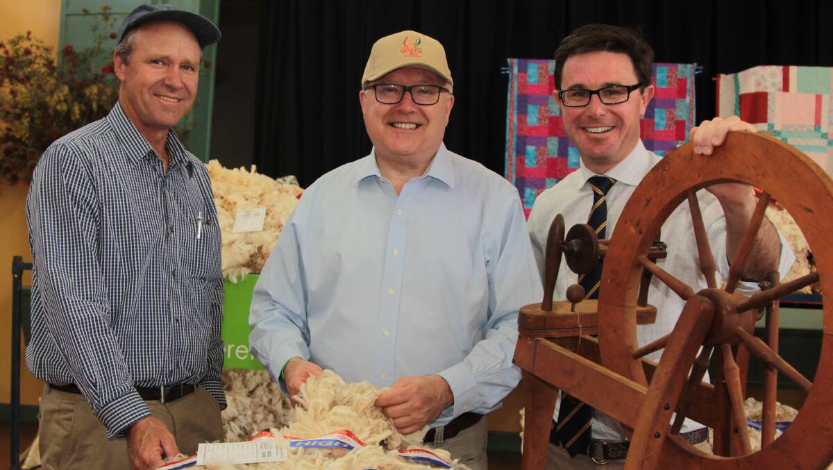 Quilpie mayor Stuart Mackenzie shows federal Attorney-General George Brandis and Member for Maranoa David Littleproud some of the superb wool grown in his shire and on display at the show.