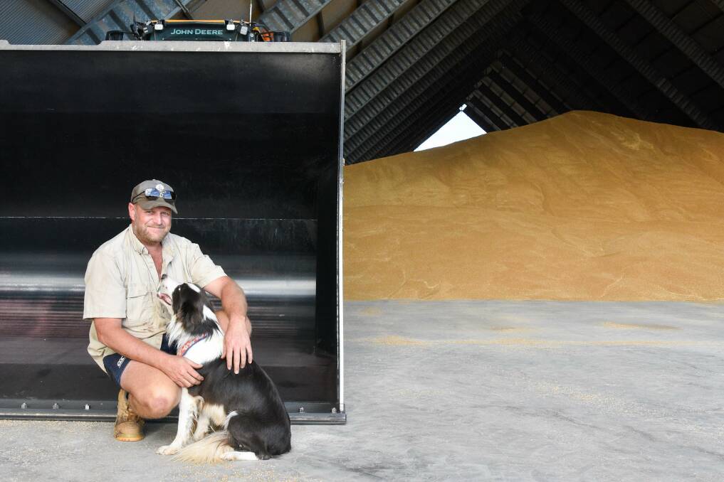 Jono with his dog Texas, next to the grain bucket and loader which Jono unknowingly picked Texas up with six tonnes of grain. PIcture: Ben Harden 