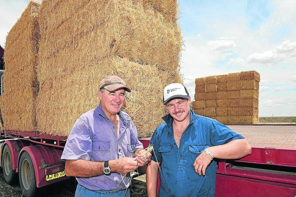 Garry and son James Houston, Terriadi, Mungindi take a breather while loading the hay. - <i>Picture: RODNEY GREEN.</i>