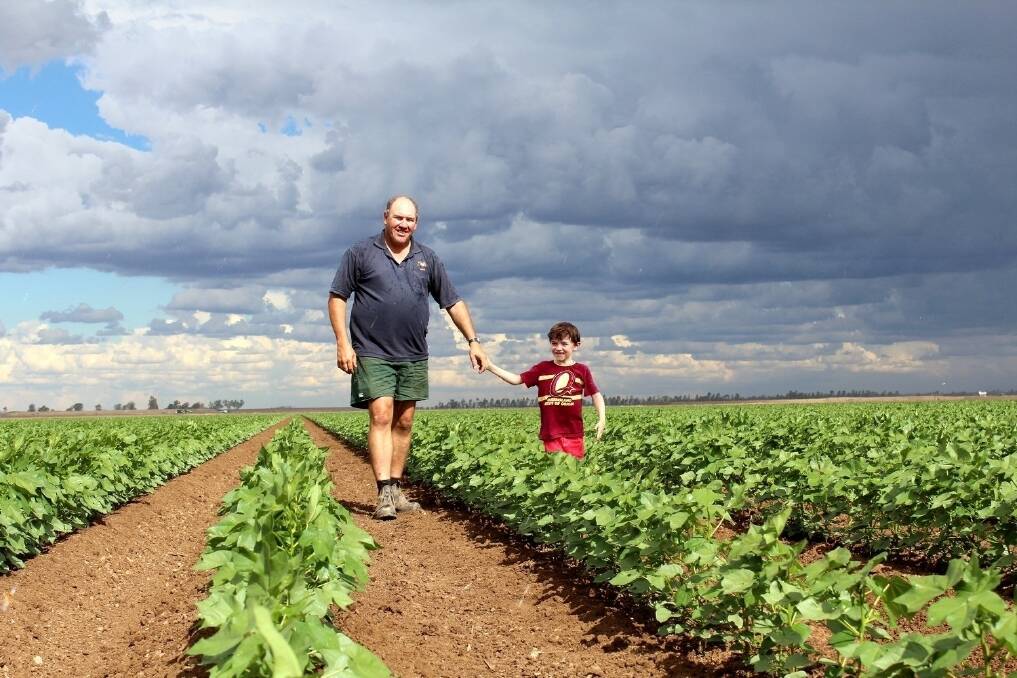 St George irrigator Scott Armstrong and six-year-old son Jeremy in this year's cotton crop. <i>Photo: Andrea Crothers</i>