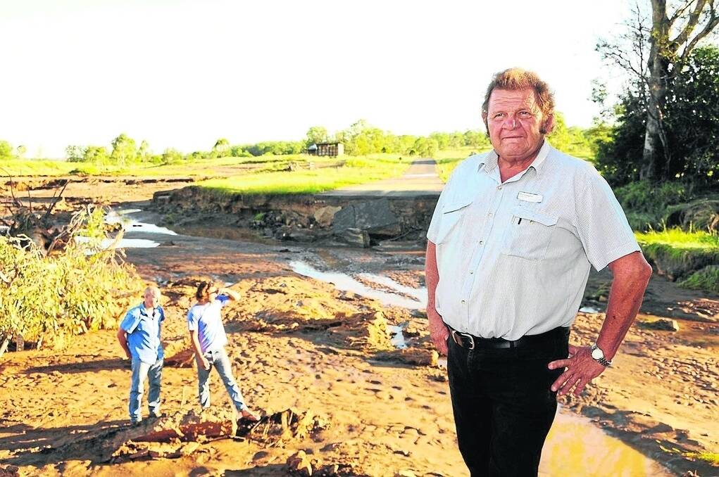 North Burnett regional councillor Paul Lobegeier of Monto inspects the flood damage along Airport Rd. Monto locals Ash Williams and Mark Leather show the six foot wash out that has destroyed the section of road.