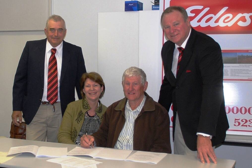 Vendors Phil and Margaret Egan signing contracts with auctioneer Peter Fleming and Elders rural property consultant Clayton Smith.