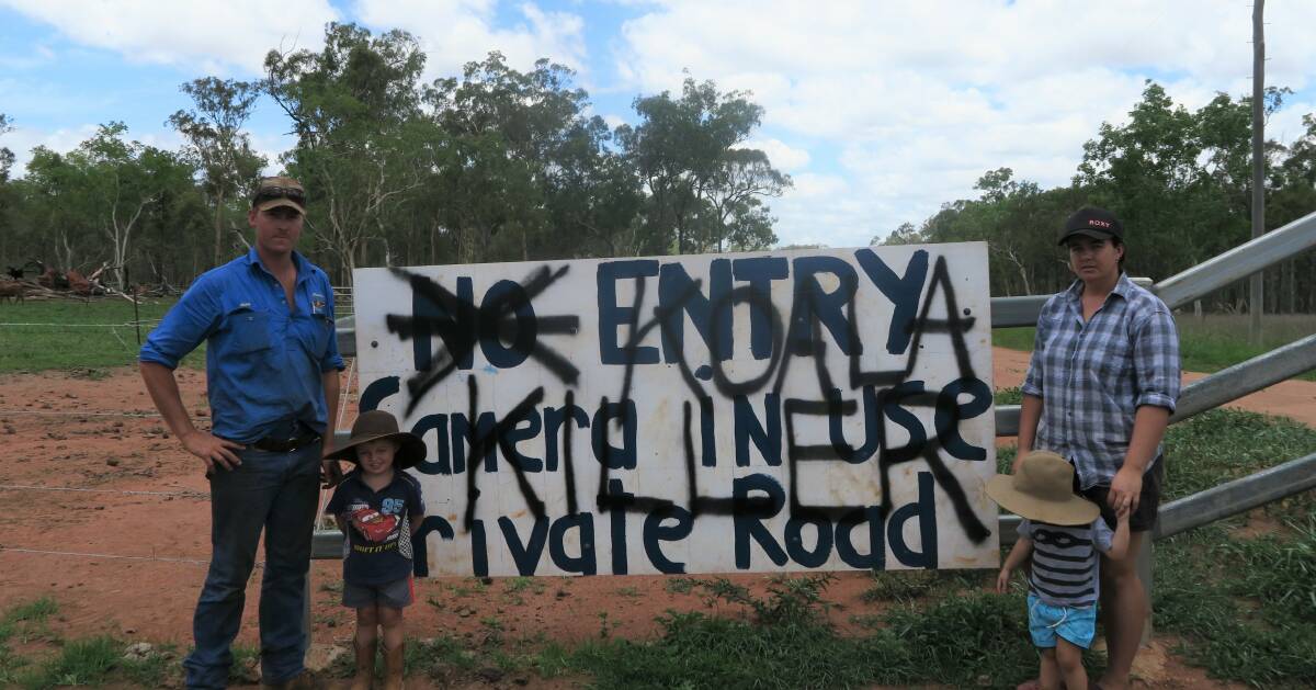 Dean and Emmalee Jonsson and their two children, William and Colby, with a sign on their property reading "Koala Killer".
