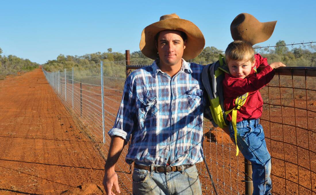 Wool producer Donald Truss from Toompine, south of Quilpie with his son Henry and a stretch of the wild dog exclusion fencing on his property.