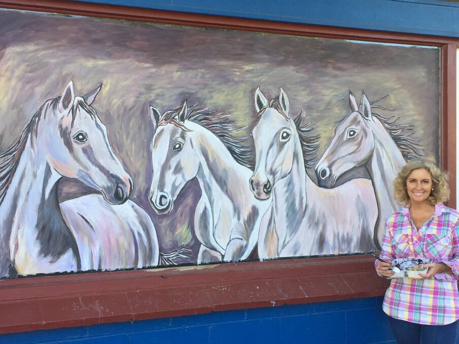 St George artist Rosemary 'Rosie' Carson and the painting of horses that she produced for the Let's Paint the Town project. She will paint another horse image on the neighbouring window.