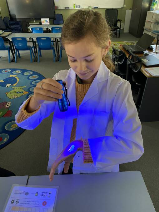 A student using a UV light to identify meat-handling residue on her hand. Picture supplied 