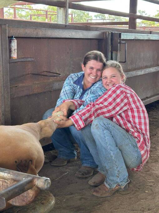 Kayla McIntyre and Chelsea Collins helping out with the farm's branding. Picture: Supplied 