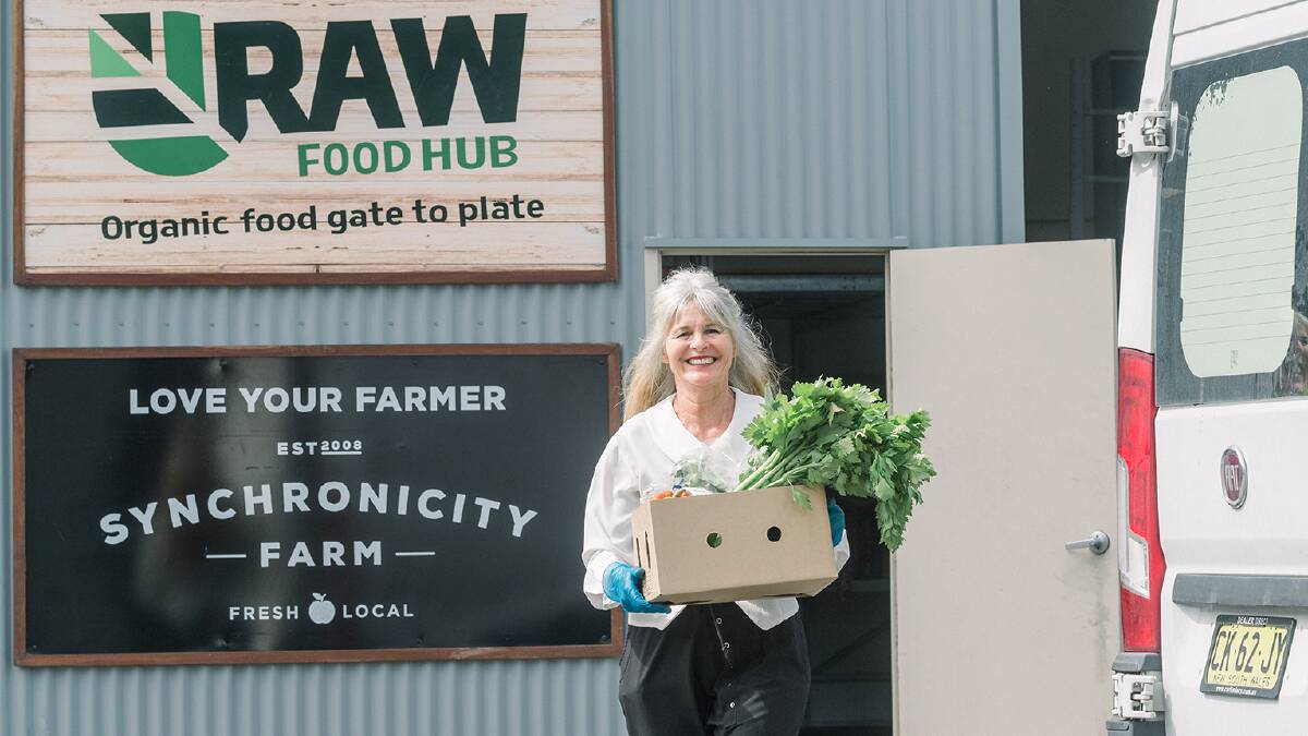 A Raw Food Hub employee loading one of the fruit and vegetable boxes for delivery. 