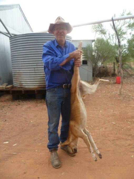 Robert Bartlett on his property near Wanarring with one of the wild dogs he has caught. Photo: Eveline Bartlett