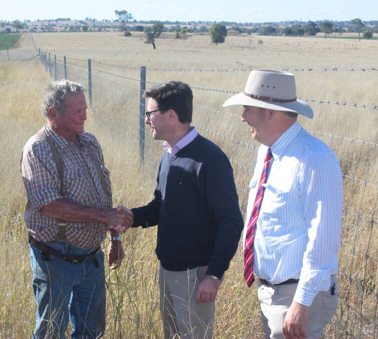 Roma livestock producer Bill Purcell shakes hands with federal agriculture minister David Littleproud as Roma mayor Tyson Golder looks on.