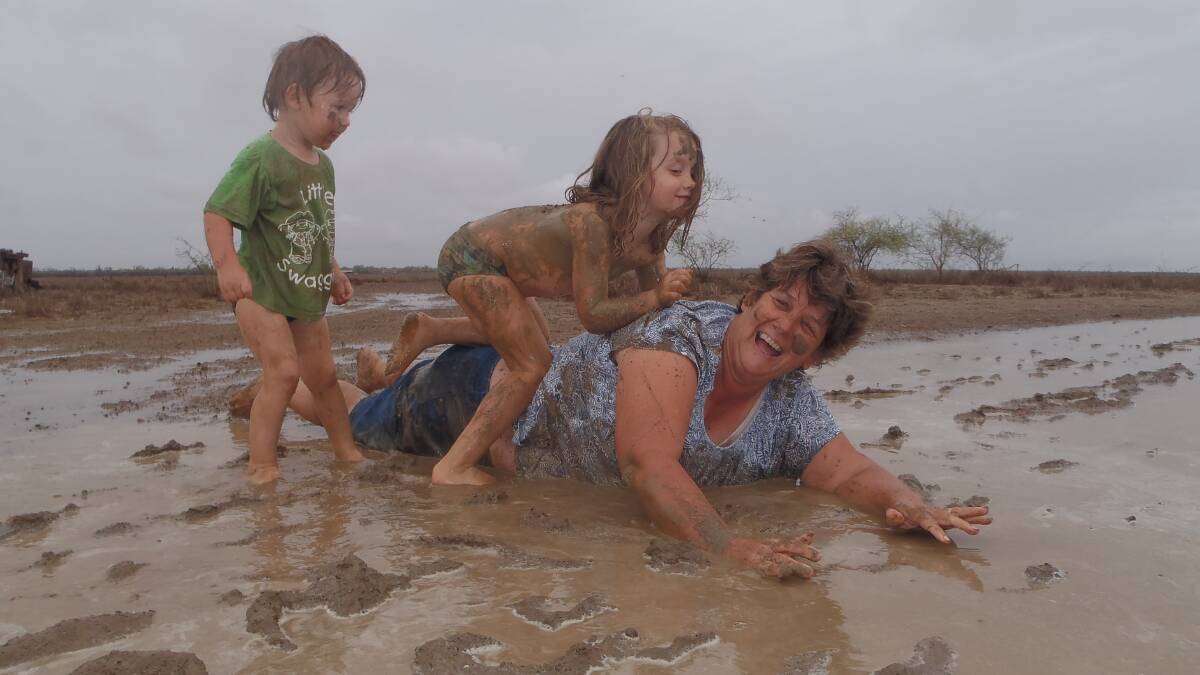 Copycat: The reputation of a well-regarded social media page to share rain reports is at stake for Winton grazier Donna Paynter, pictured enjoying a recent 44mm downpour with her grandchildren Amber and Logan Ellis. Picture: Heidi Paynter.
