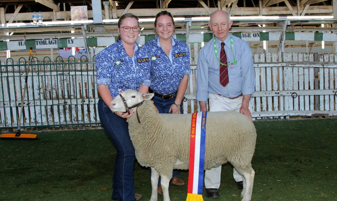 Pride of the Downs sisters Erin and Georgia Lee holding the champion White Suffolk ewe and supreme champion ewe of the show, with judge, George Melano.