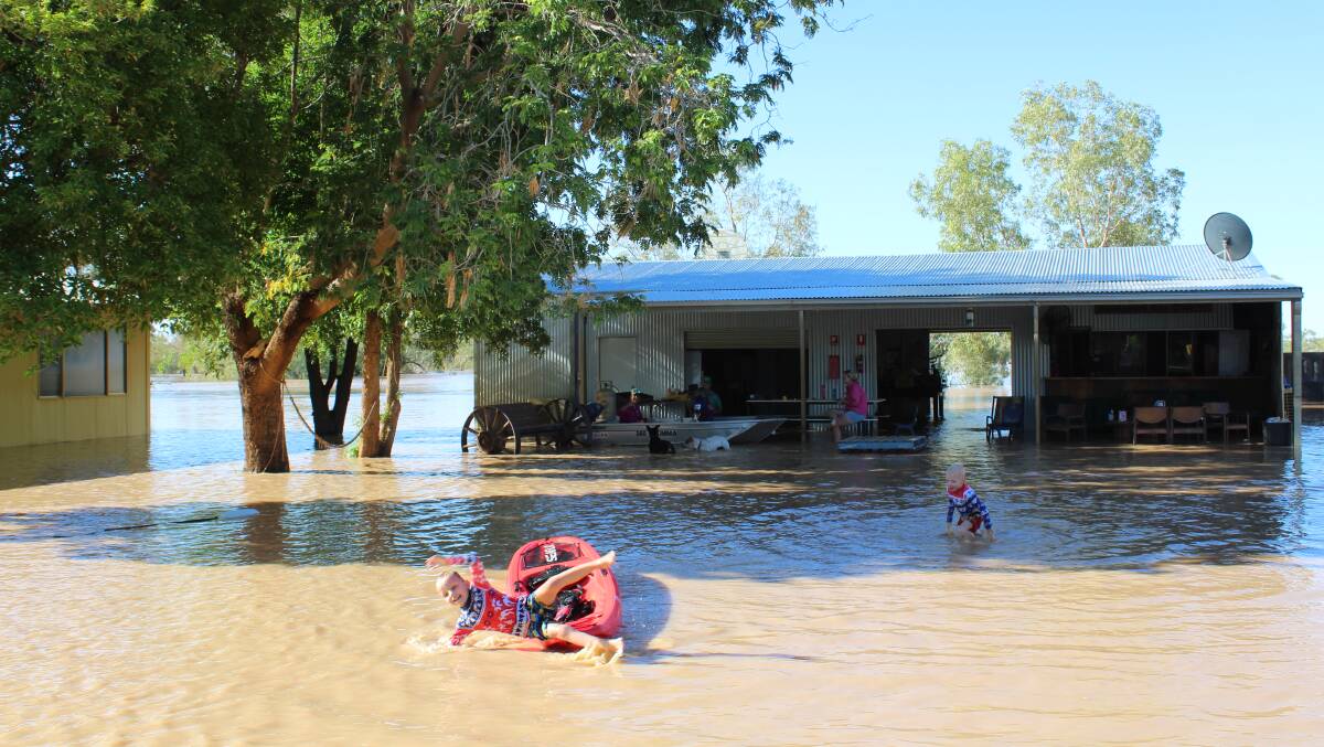 Benjamin and Alexander Myhill frolic in the floodwaters at Davenport Downs, while Alayia Staib and Zach Weir contemplate the scene in their tinny, along with Mitchell Stewart and Corri Deighton in front of the staff social club.