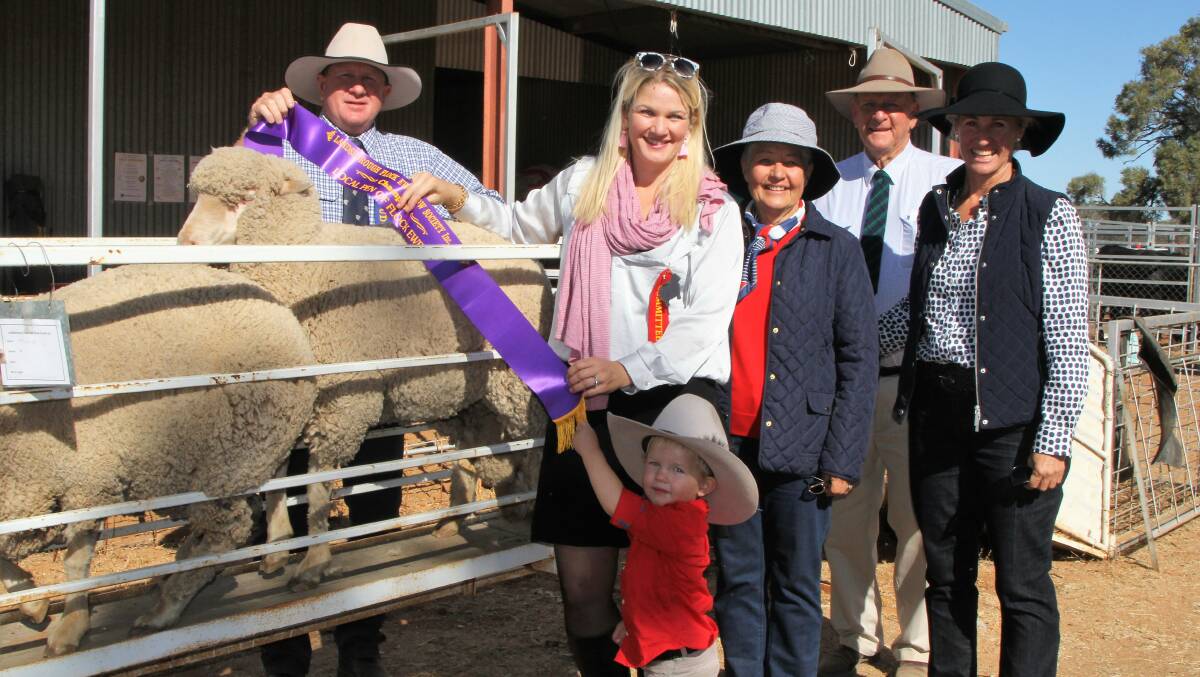 Flock Ewe Show judge Justin Campbell and Amanda Button, with help from Albert Button, sash the champion production Merino ewe, shown by Julann, Bill and Annabell Chandler, Hillalong, Barcaldine.