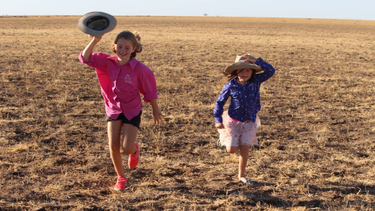Cousins Amber Ellis and Ruby Paynter searching for any grasshoppers remaining on the paddocks at Wando Station, south of Winton. Picture - Donna Paynter.