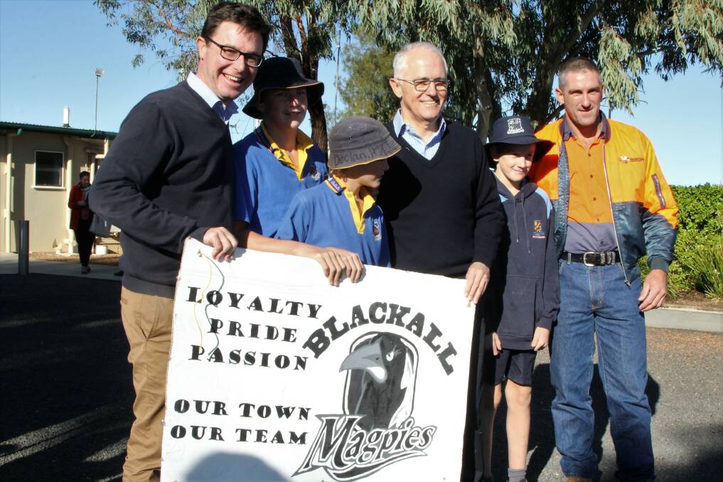 Australian prime minister, Malcolm Turnbull, together with Agriculture Minister, David Littleproud, getting in the Magpies spirit at the Blackall airport.