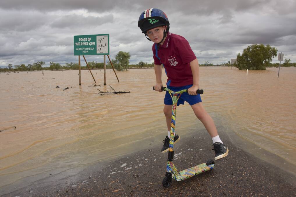 Ethan Cox, Warrnambool Station, testing out his new scooter beside the flooded Western River on Winton's western outskirts. The scooter was a birthday present that he waded through mud and water to get to. Picture - John Elliott.