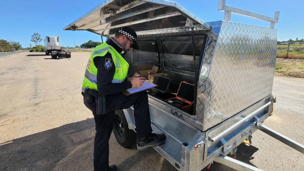 Constable Chris Curtin recording car and caravan weights at Longreach, before sharing the results with drivers.