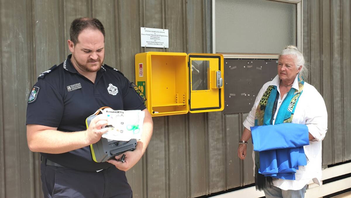 Constable Shane McGregor explains how the defibrillator works once unlocked with a PIN code, while Dulacca Memorial Hall & Progress Association president Adele Hughes watches on.