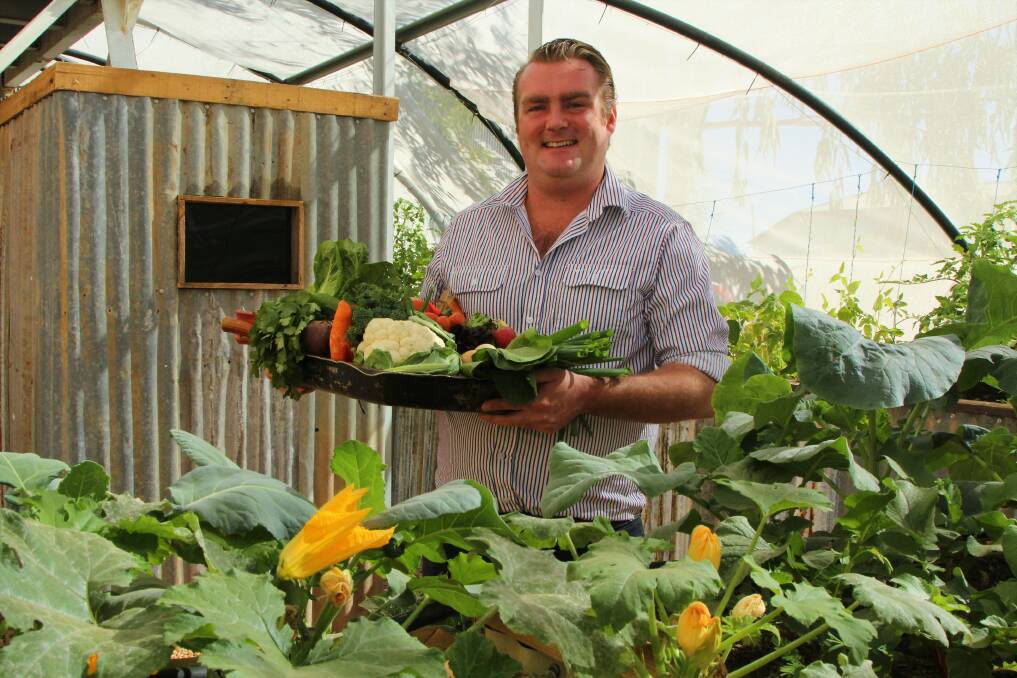 Tank to table: Ben Casey shows off some of the fresh produce from the North Gregory aquaponics garden, with one of the fish tanks in the background. Picture: Sally Cripps.