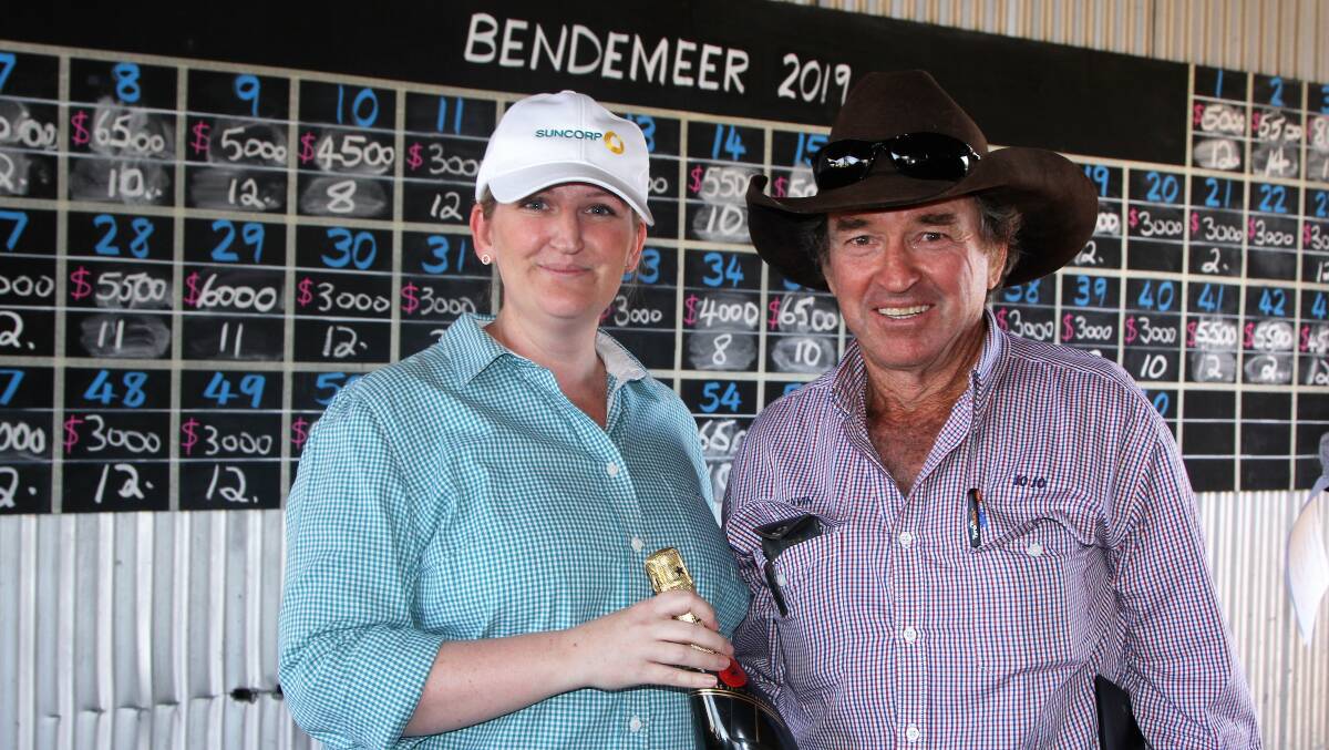 A Suncorp representative presents Gavin Vallis with a bottle of bubbly for his top price purchase following the Helmsman auction.