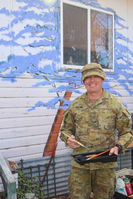 Lance Corporal Gregory Meyer from the 6th Battalion, Royal Australian Regiment, repainted the jacaranda mural on Mrs Ellis' home in Hebel.