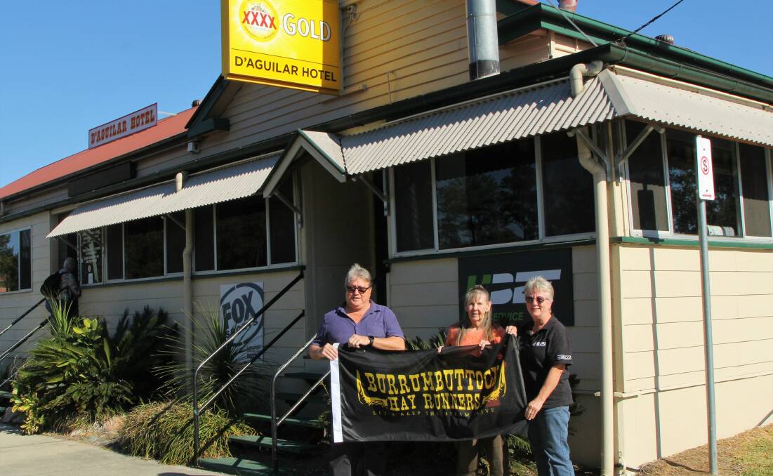 Helping hand: Jim 'Cricket' Mitchell, Pam Hession and Lyn Bowen fly the Burrumbuttock Hay Runners flag outside the D'Aguilar Hotel in honour of the latest fundraising effort that took place at the Woodford cattle sale. Picture: Sally Cripps.