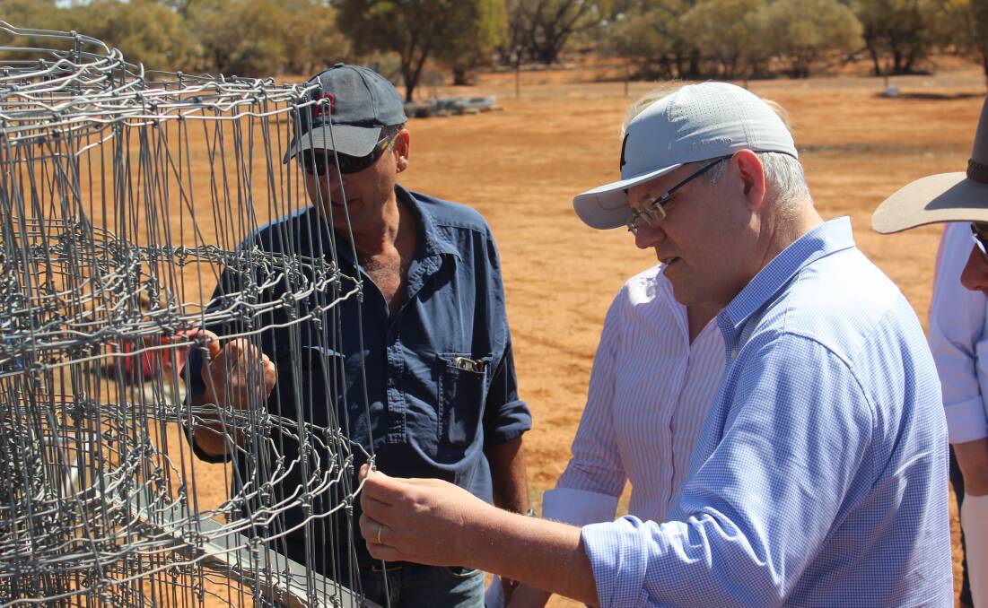 Stephen Tully talks Prime Minister Scott Morrison through the process of building an exclusion fence. 