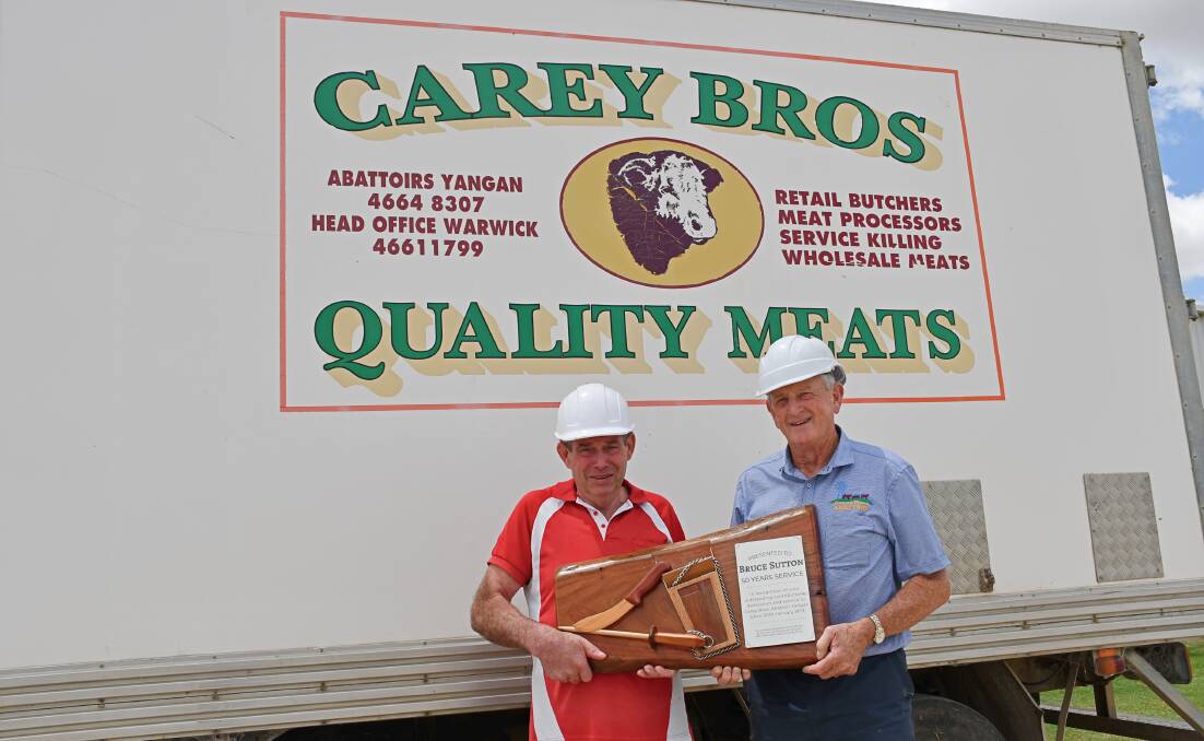 Bruce Sutton accepts the specially-made plaque to mark his 50 years of service from Carey Brothers owner Greg Carey. Picture: Billy Jupp 