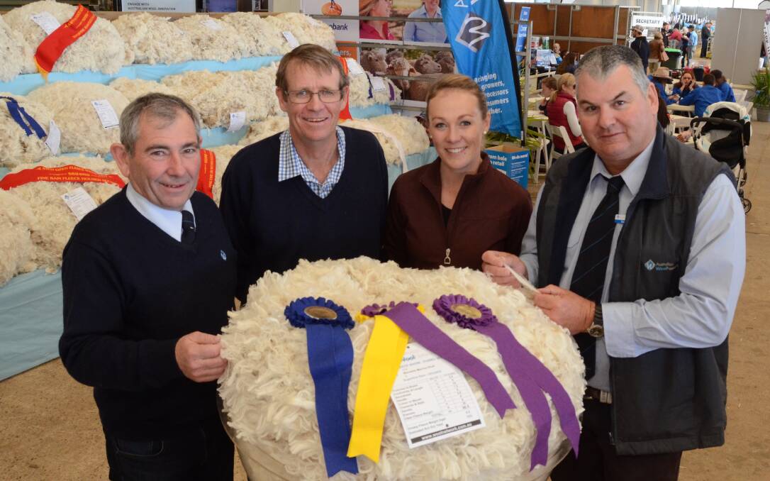 Fleece judges from Australian Wool Network, Harold Manttan, Uralla, (left) and Greg Hunt, Longreach, Qld, (right) flank the exhibitors of the grand champion 17-micron fleece, Malcolm and Bec Cox, Bocoble stud, Mudgee.
