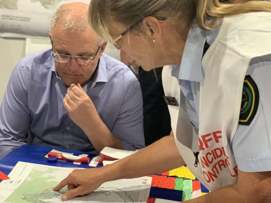 MAPPING: QFES area director Kaye Healing shows the Prime Minister where the fire fronts are. Photo: Larraine Sathicq