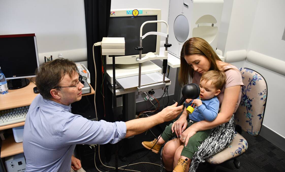 QEI's lead clinical scientist Timothy Stark demonstrating the electroretinogram machine with Max Thomson and his mum Alanna.