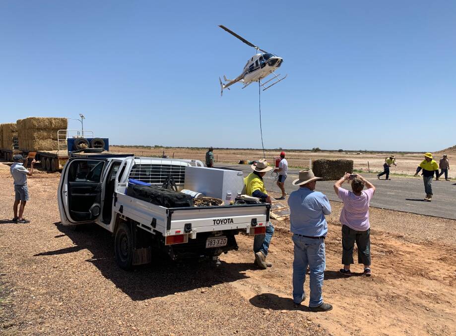 A commercial helicopter pilot lifts Rural Aid hay from outside Winton. 