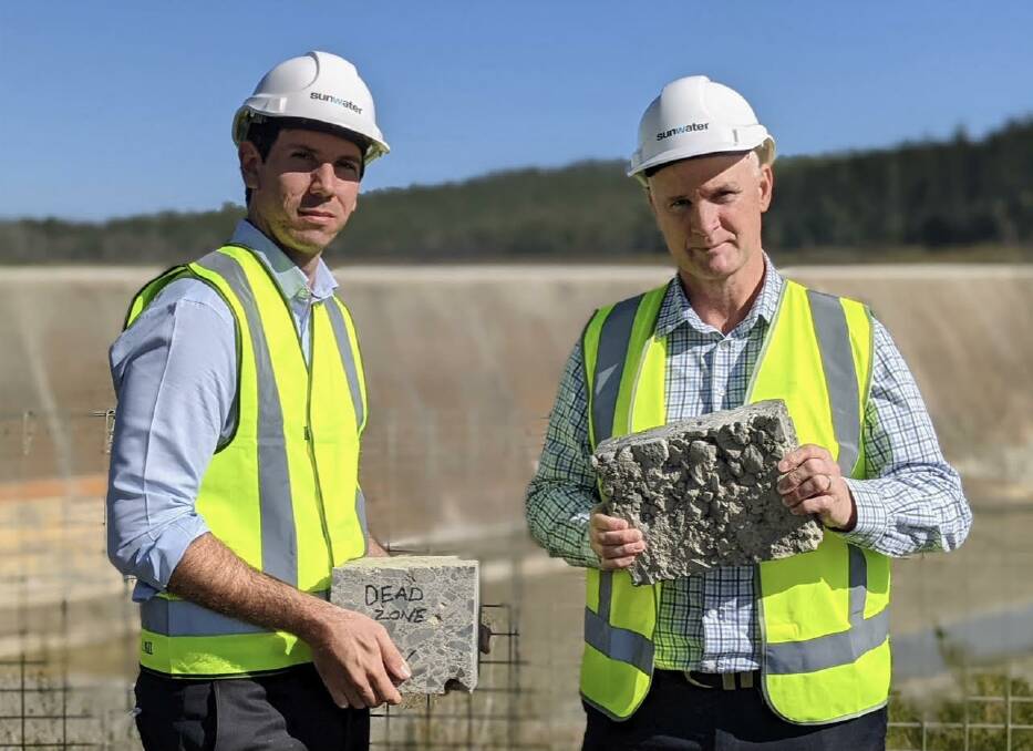 Bundaberg MP Tom Smith and Water Minister Glenn Butcher, Gladstone, pictured in front of the Paradise Dam wall in late July. Both MP's are holding a sample of a roller compacted concrete, which is behind the government's dam remediation. 
