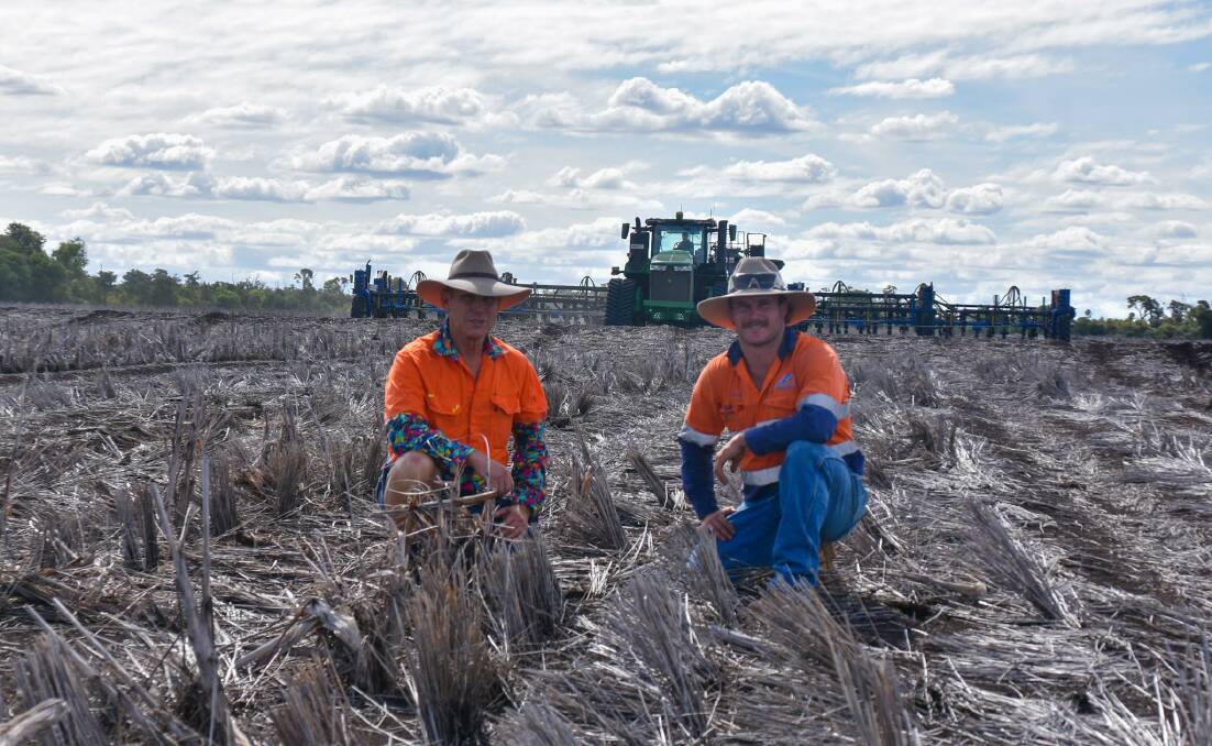 David and Lawson kneeling in the field set to be planted to wheat, with Lawson's father Alan Storey on the planter in the background. Picture: Ben Harden 
