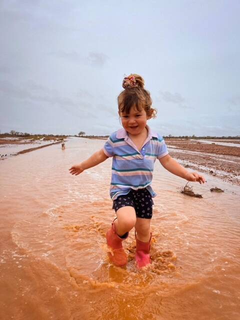 Brydie Hahn, 3, and dog Sally play in the puddles after 35mm of rain fell this week at Burkobulla Station north of Eromanga. Photo: Heather Hahn 