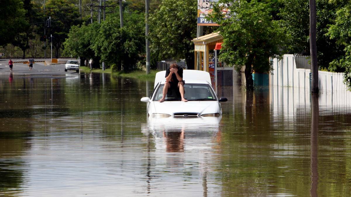 A man waits for rescue after stalling his car while attempting to drive through the floodwaters in Rockhampton in the 2011 floods. Photo: Janie Barrett