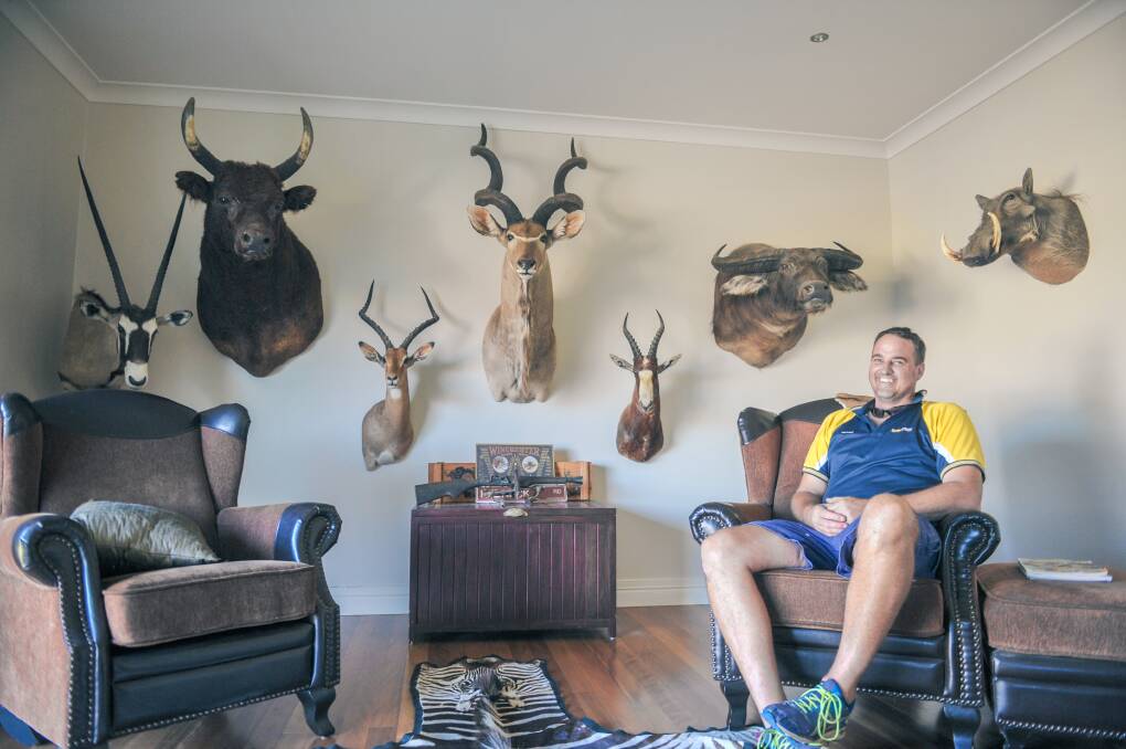 Peter Smith sits in the trophy room with his hunting successes. 