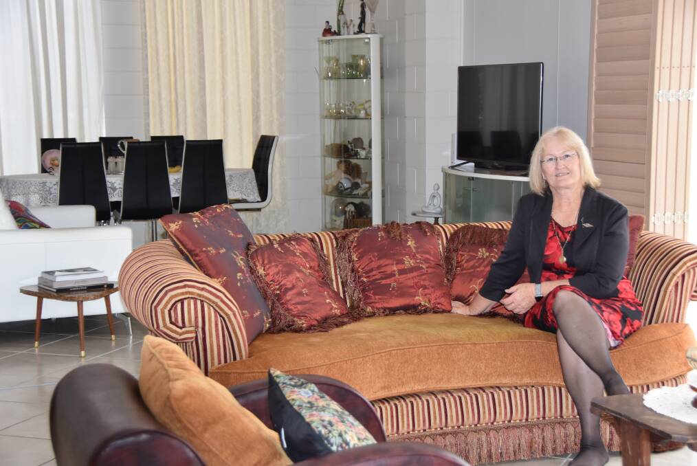 Liz Schmidt sits in her formal living room, with the modern entertainment area pictured in the background. Photo: Jessica Johnston.
