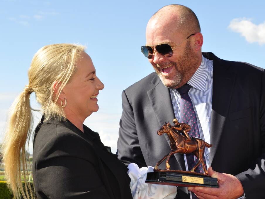Trainer of Mason's Chance Olivia Cairns accepts the Battle of the Bush trophy from Racing Queensland's ambassador, Peter Moody. 