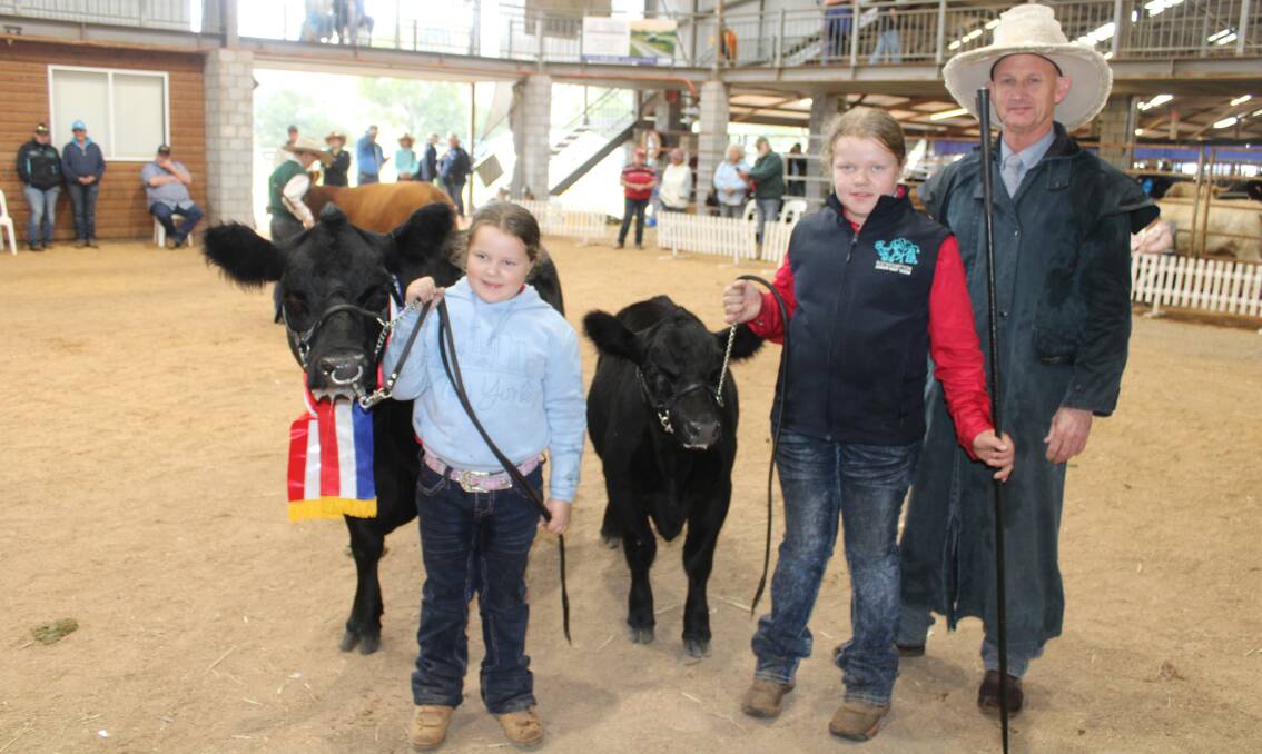 Grand champion small breeds female MWL Mia held by Wyatt Iseppi, while Macie Iseppi holds the bull calf at foot beside judge David Greenup. 