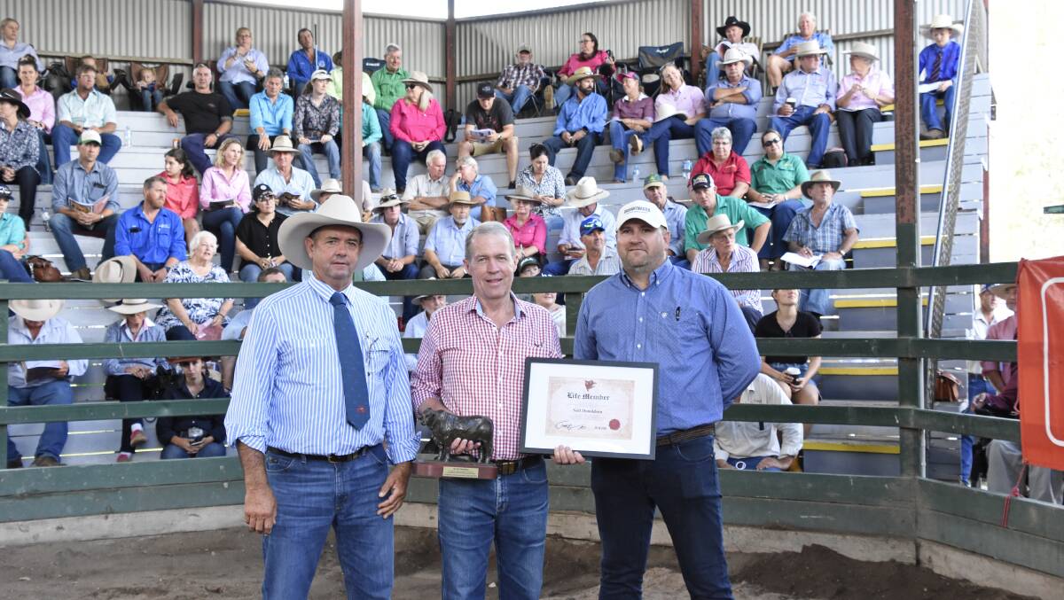 Former society president Rob Atkinson and current president Todd Heymann presented former society chief executive officer Neil Donaldson (centre) with life membership of the Droughtmaster Stud Breeders' Society on Saturday.