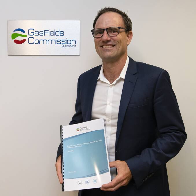 GasFields Commission Queensland Acting CEO Warwick Squire holding the Review of the Regional Planning Interests Act 2014 Assessment Process Report. 